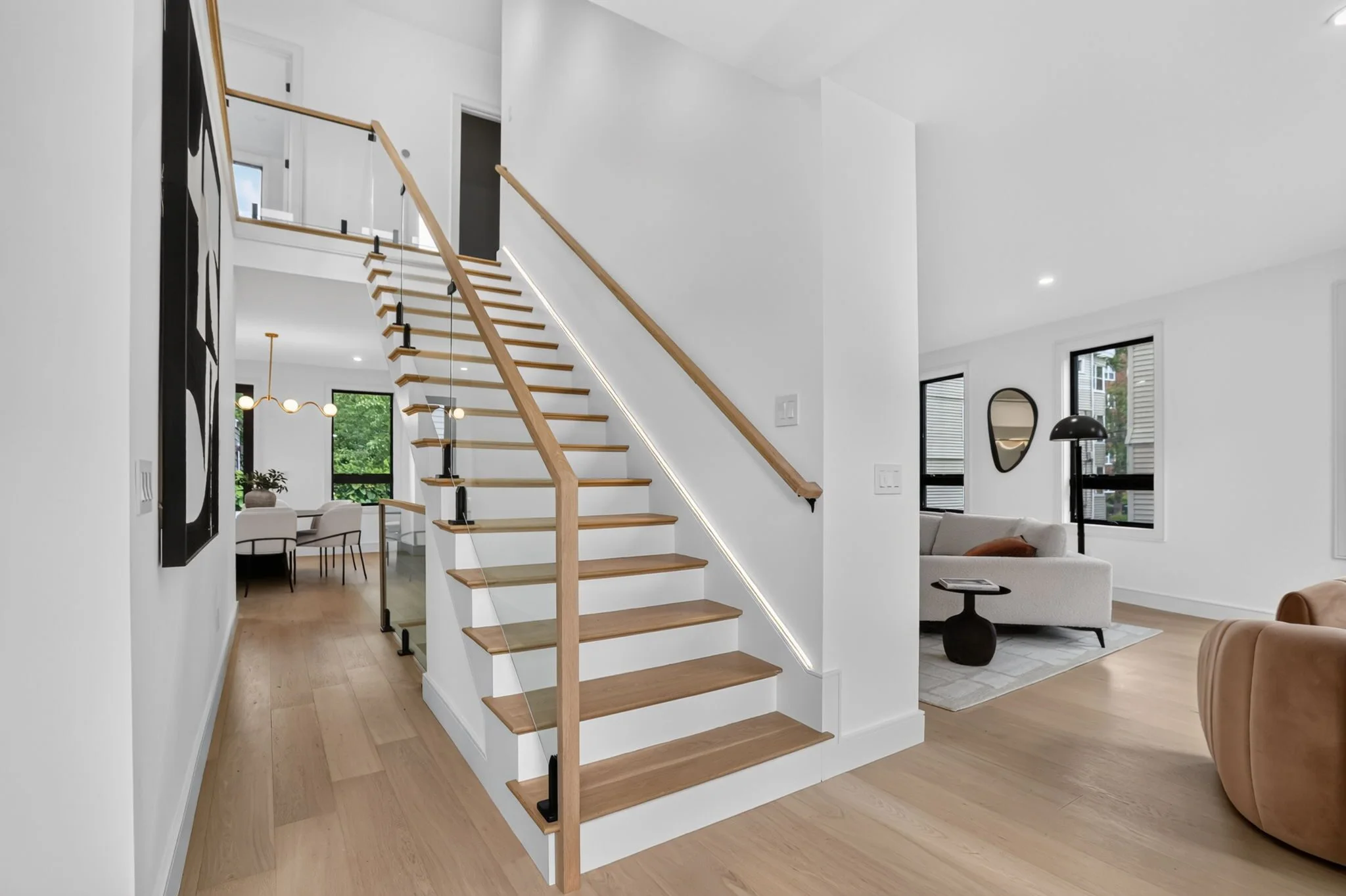 Sunlit entry with a sculptural open-riser staircase